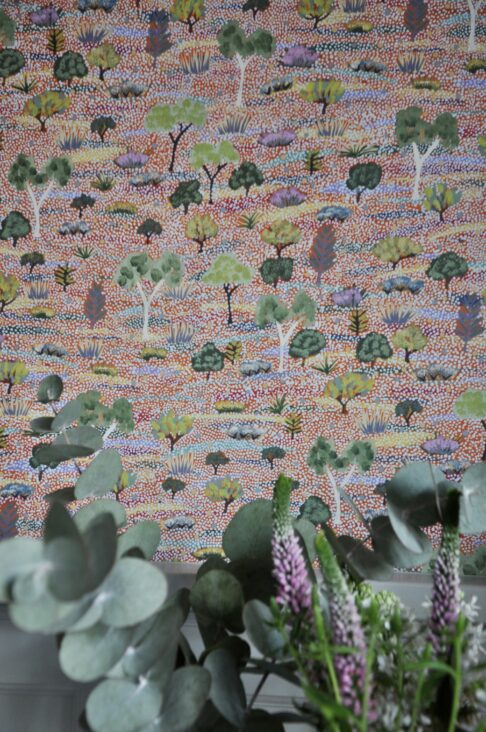 Aboriginal art wallpaper detail with Eucalyptus and flowers in the foreground.