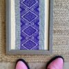 Framed textile art showcasing Thai hand loomed textiles in a regal, purple hue.