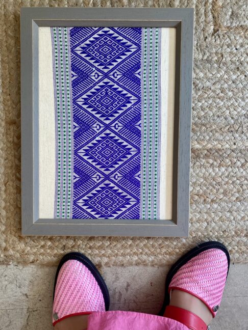 Framed textile art showcasing Thai hand loomed textiles in a regal, purple hue.