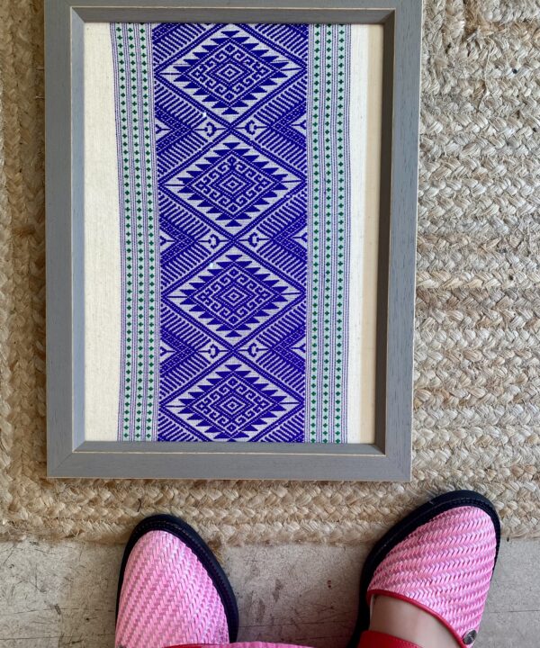 Framed textile art showcasing Thai hand loomed textiles in a regal, purple hue.