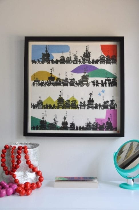 A colourful framed Japanese silkscreen above a dressing table.