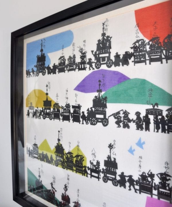 A colourful, Japanese silkscreen print depicting the Gion festival in a simple, black frame.