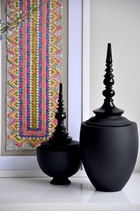 Matt and gloss black decorative lidded pots in two sizes.