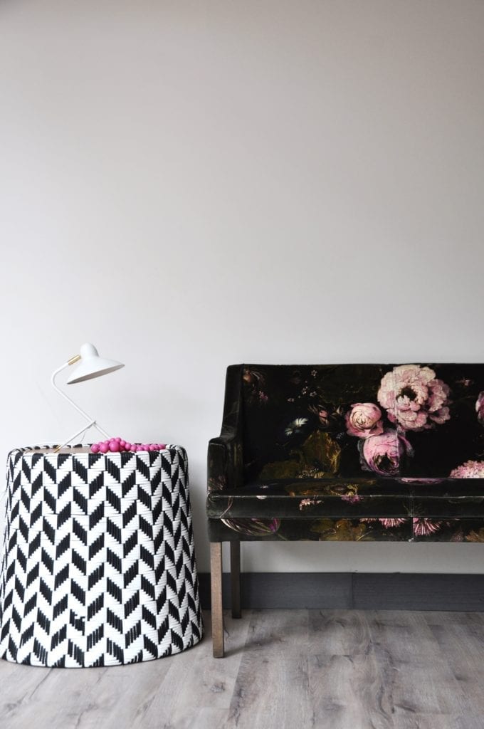 A striking, black and white woven side table, sourced in Chiangmai Thailand, sat next to a floral-upholstered bench seat.