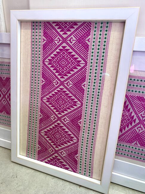 A smaller, portrait framed Thai textile pink wall art adds colour and culture.