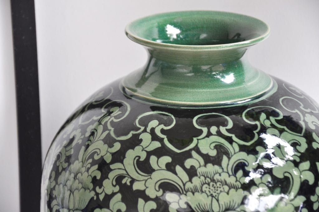 The elegant, narrow neck of a hand-painted, glazed celadon pot from northern Thailand.