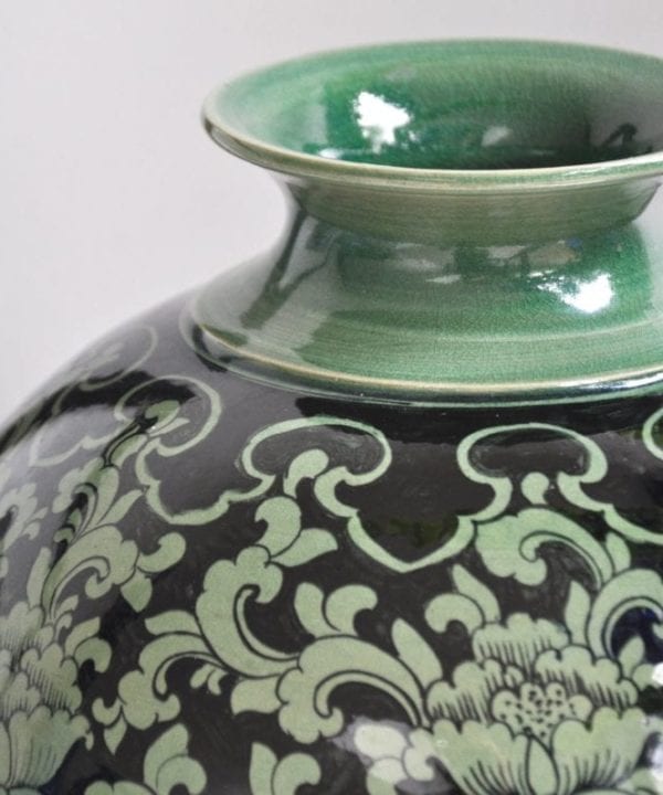 The elegant, narrow neck of a hand-painted, glazed celadon pot from northern Thailand.