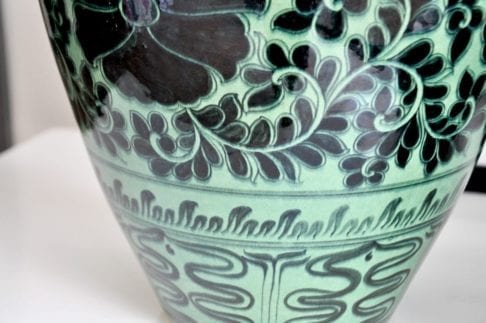 Detail of an Asian pottery green pot, hand-decorated with Lotus flowers.