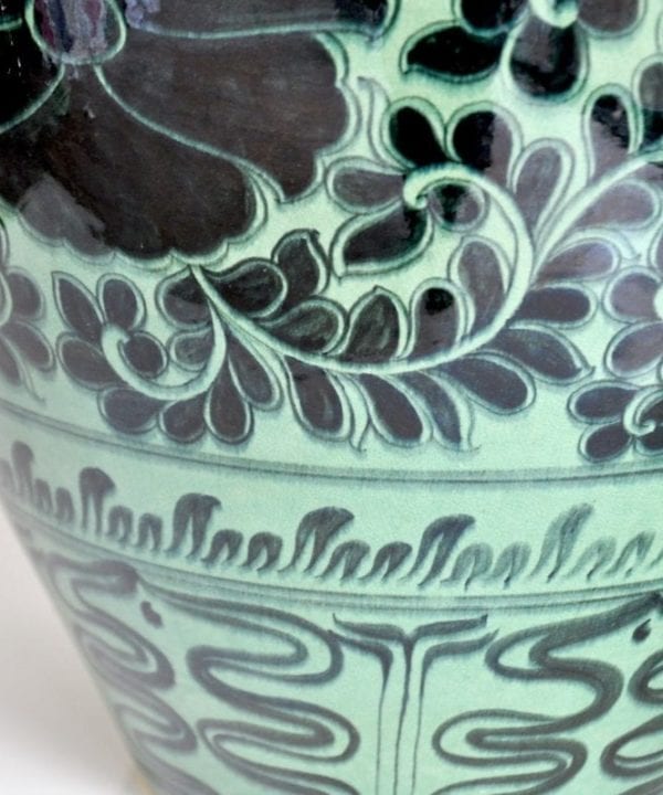 Detail of an Asian pottery green pot, hand-decorated with Lotus flowers.