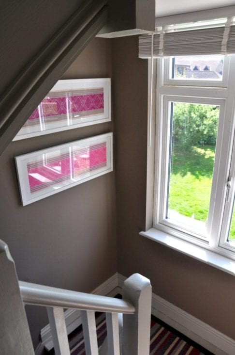 A pair of landscape-framed Thai textiles in magenta and baby pink.