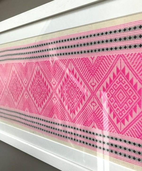 A framed candy pink and navy woven Thai textile.