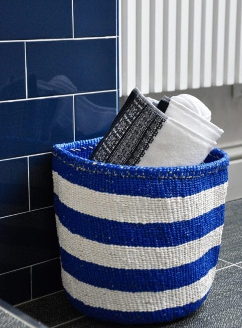 Stylish, striped storage baskets in a Royal blue hue shown here with towels in a bathroom.