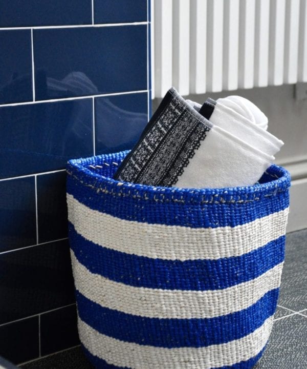 Stylish, striped storage baskets in a Royal blue hue shown here with towels in a bathroom.