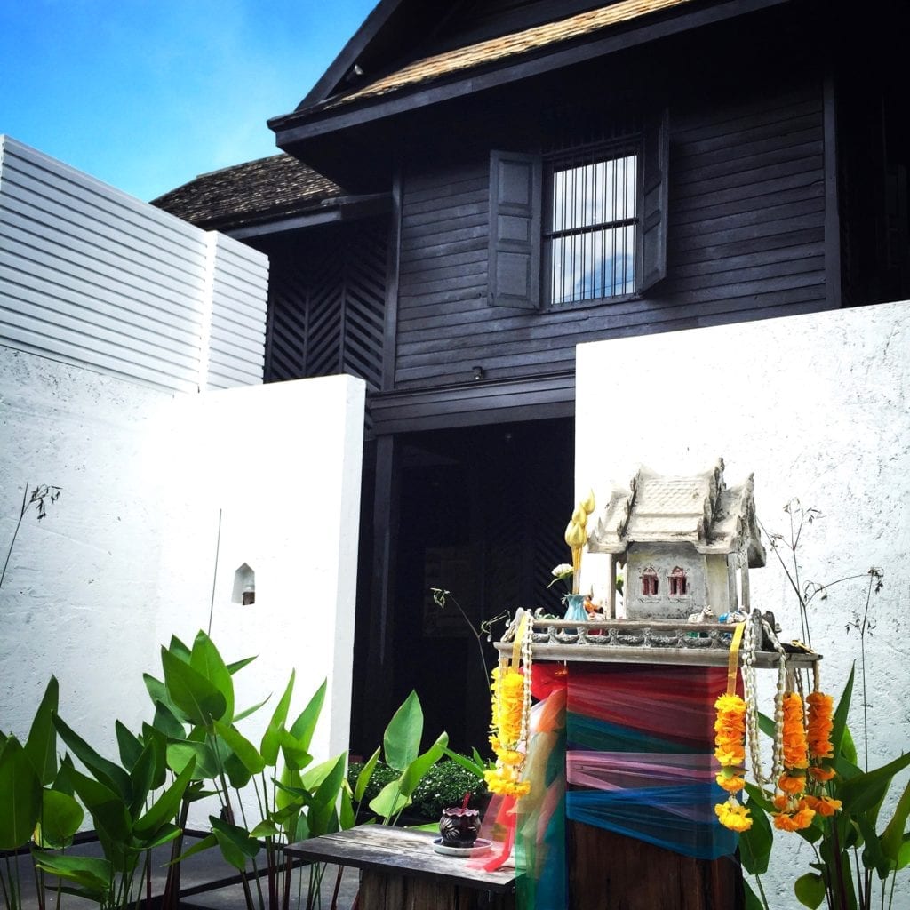 A traditional Thai spirit house in front of a contemporary hotel in Chiangmai, northern Thailand.