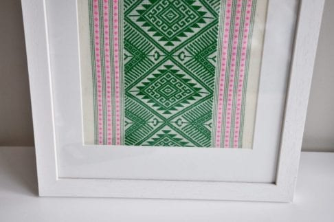 A simple white frame elevates this culturally-inspired, hand-woven Thai textile in green and baby pink.