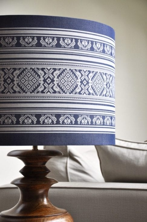 Close-up shot of a large, drum lampshade in a blue and white woven stripe fabric that was inspired by Hungarian folk motifs.