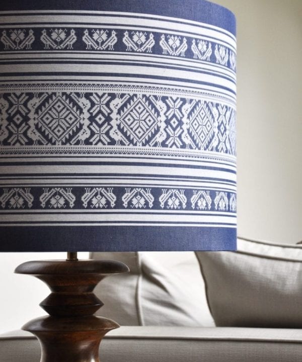 Close-up shot of a large, drum lampshade in a blue and white woven stripe fabric that was inspired by Hungarian folk motifs.