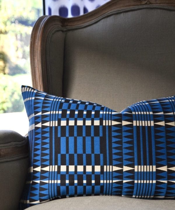 A blue geometric cushion with an African, tribal-pattern-inspired design on a French armchair.