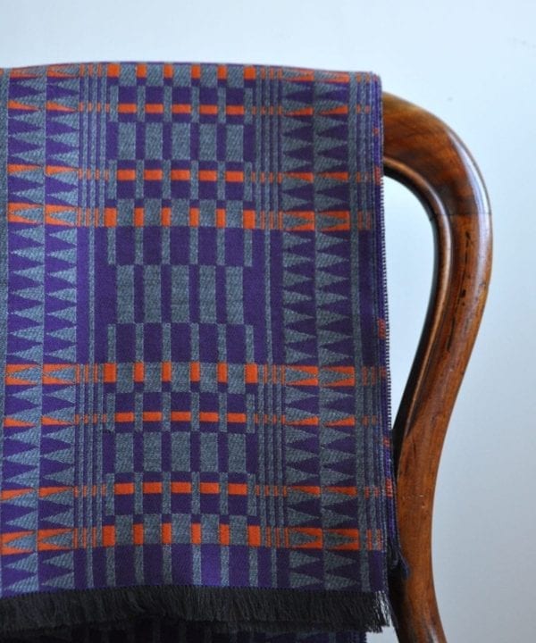 A purple, orange and grey, fringed wrap scarf in the softest cashmere hung on the back of an antique, balloon back dining chair.