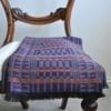 Purple cashmere wrap scarf with orange accents on a vintage chair.