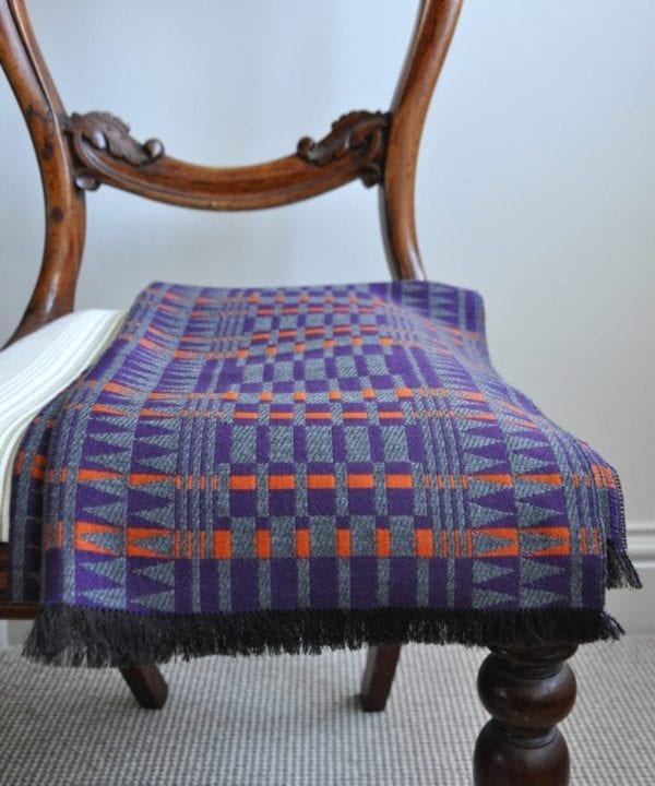 Purple cashmere wrap scarf with orange accents on a vintage chair.