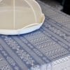 Detail of a luxury, blue linen tablecloth with Arabian architectural motifs pattern with an elegant white Thai style food cover.