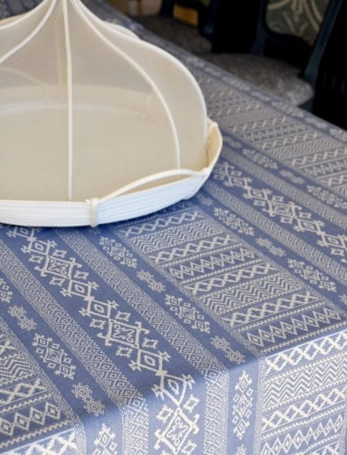 Detail of a luxury, blue linen tablecloth with Arabian architectural motifs pattern with an elegant white Thai style food cover.