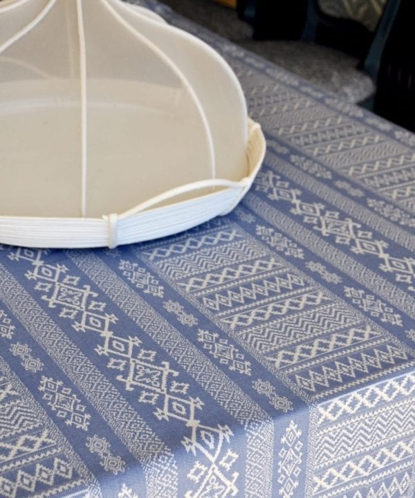 Detail of a luxury, blue linen tablecloth with Arabian architectural motifs pattern with an elegant white Thai style food cover.