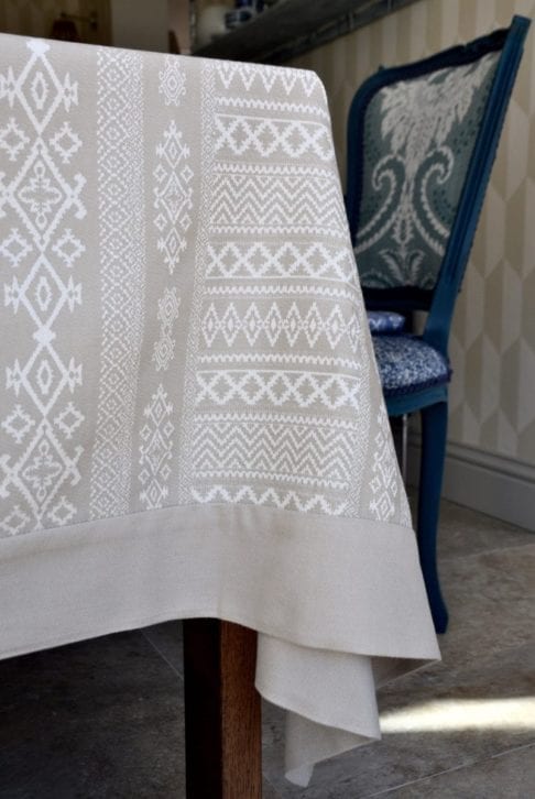 Close-up image of our neutral tablecloth with elegant Arabian architectural detailing in the weave, styled on a dining table.