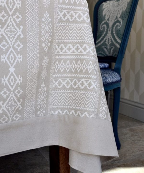 Close-up image of our neutral tablecloth with elegant Arabian architectural detailing in the weave, styled on a dining table.