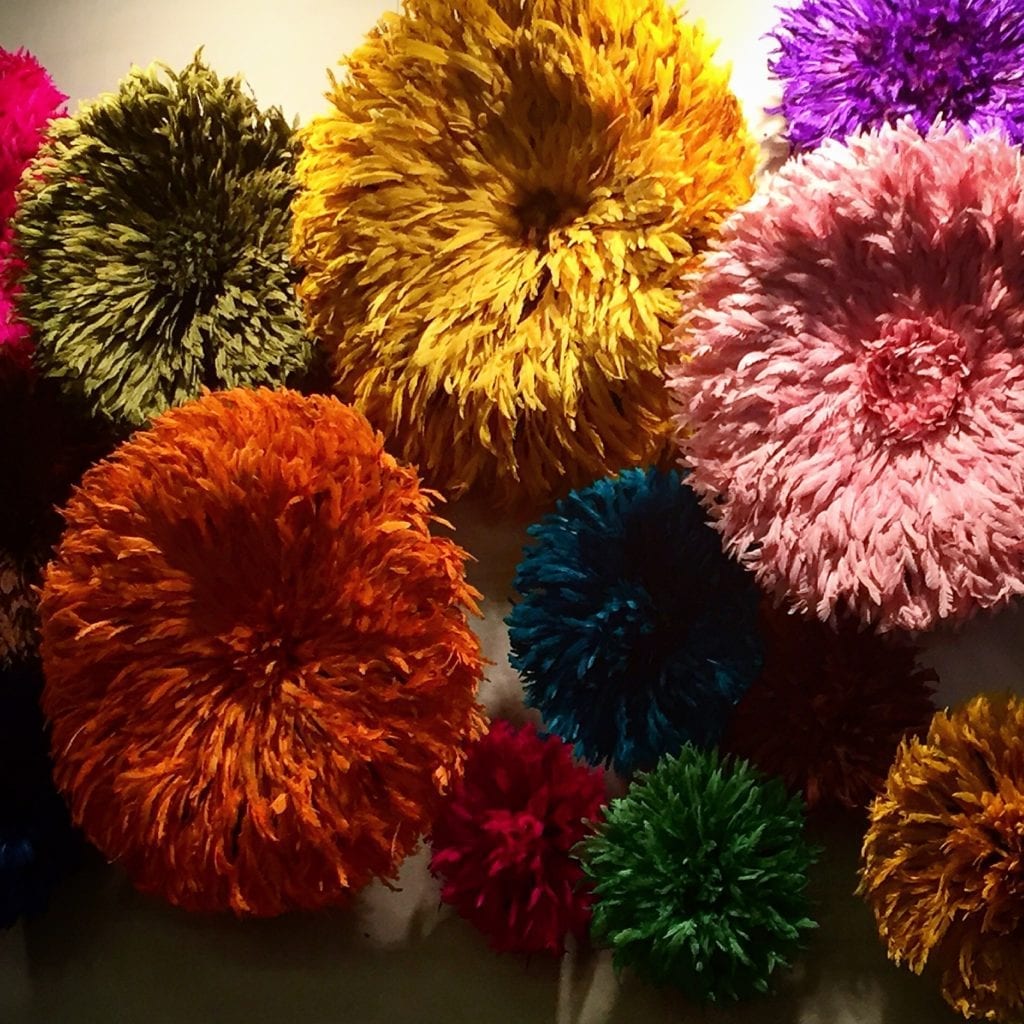 A wall display of colourful. African. tribal Juju hats made from feathers.