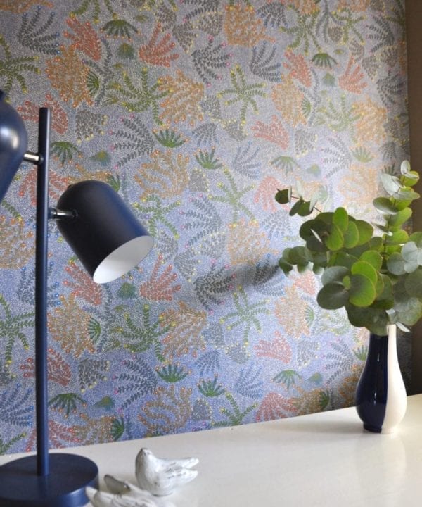 A blue angle poise lamp in foreground with blue floral Aboriginal symbols wallpaper.