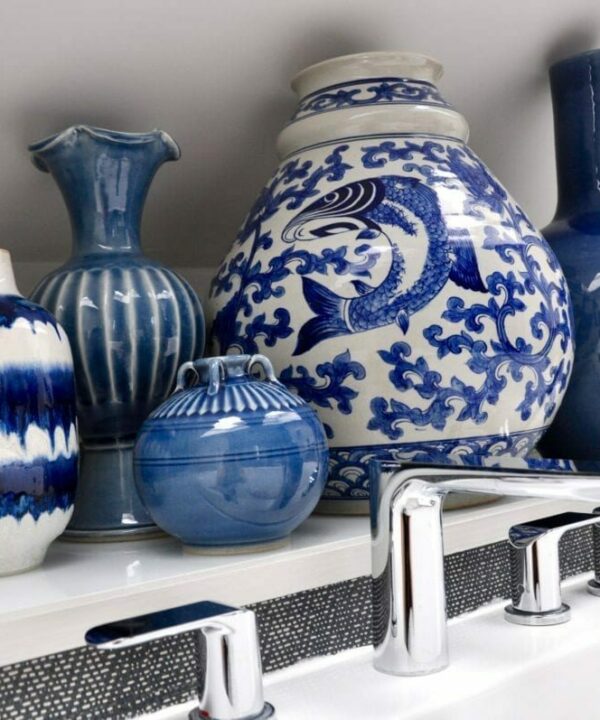 A large blue and white pot surrounded by smaller, decorative pots in the same classic colour combination and styled in a modern bathroom setting.