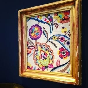 Colourful embroidered textile in a vintage frame.