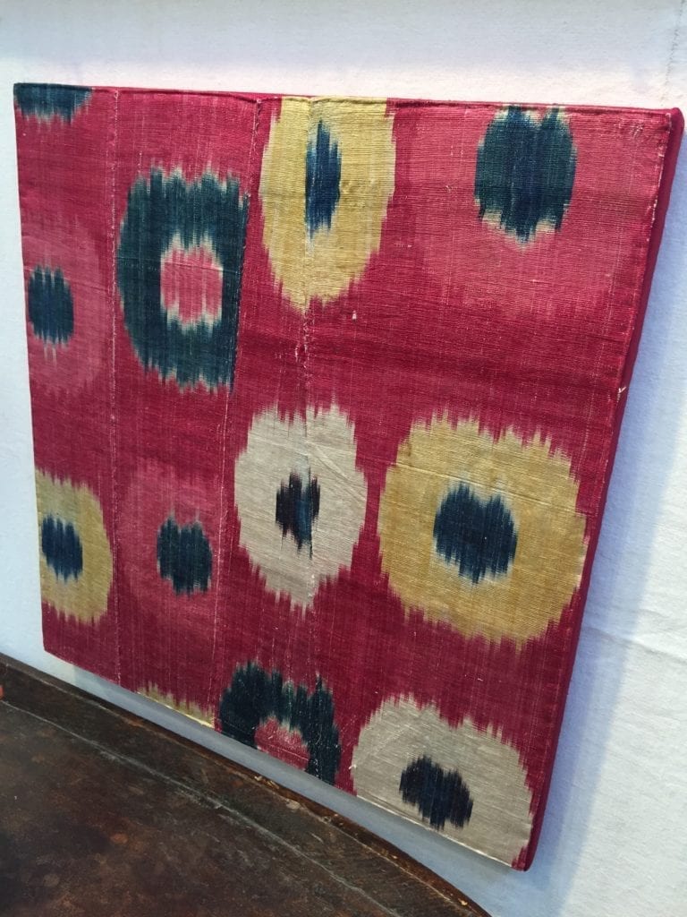 A vintage silk ikat textile stretched on a canvas for display.