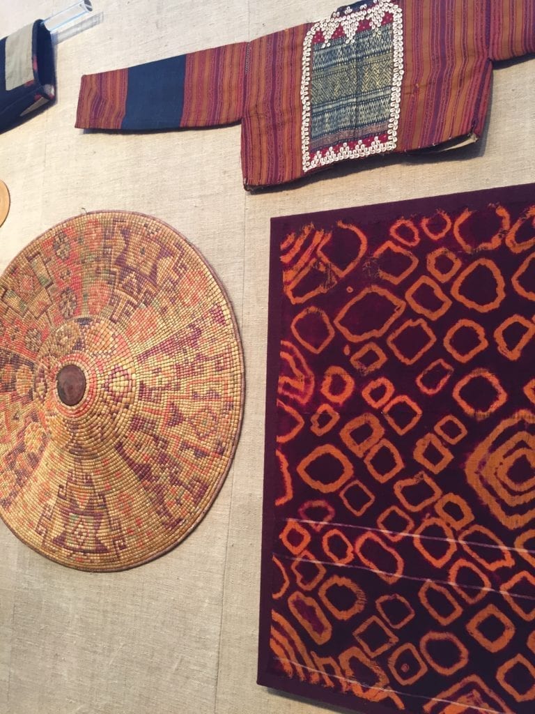 Cultural textiles and artefacts displayed on a wall.