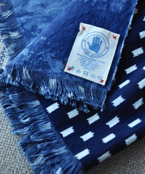 Shot of an indigo blue check scarf showing the Blue Handed label.