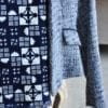 Close-up of a geometric print cotton scarf hung on a ladies blue tweed jacket on a chair.