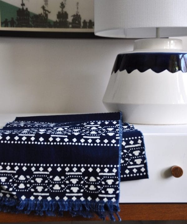 An Asian style indigo stripe scarf on a dressing table with a ceramic table lamp.