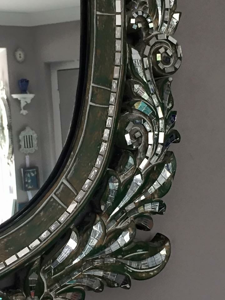 A detail of the top right hand corner of a mirror mosaic green carved wood mirror from Thailand.