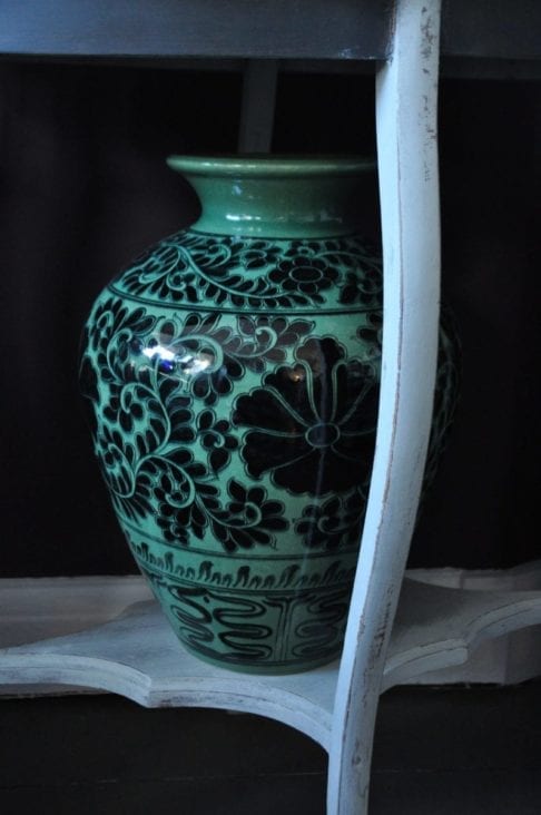 A large, patterned urn-shaped pot in deep green colour with black Thai cultural motifs and a Lotus flower design.