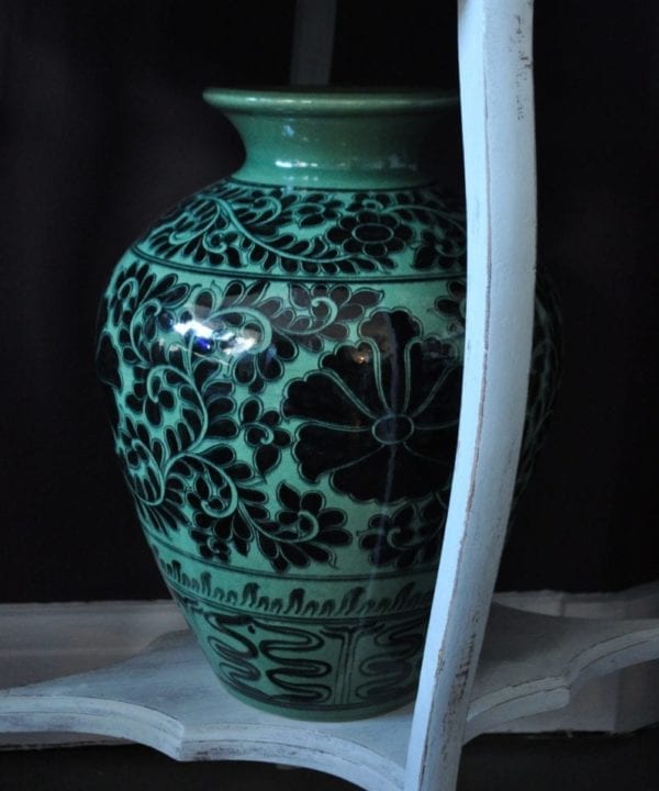 A large, patterned urn-shaped pot in deep green colour with black Thai cultural motifs and a Lotus flower design.