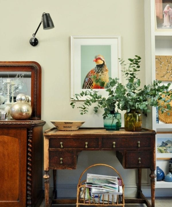 A giclée digital art print of a partridge above a mahogany desk and vase with eucalyptus.