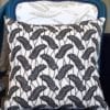 A chic black and white botanical cushion in African Dutch wax print fabric on a blue French chair.