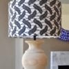 A stylish monochrome drum lampshade available in two sizes teamed with a simple, urn-shaped wooden base.