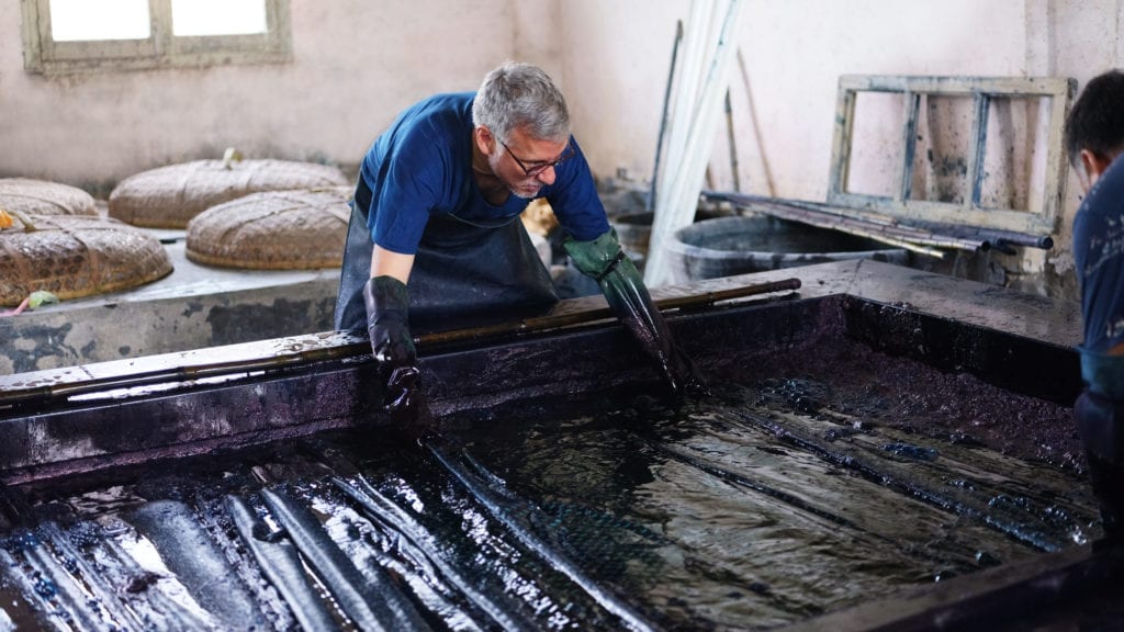 John Abbate gets truly 'blue handed' while dipping the cloth in the indigo vat.