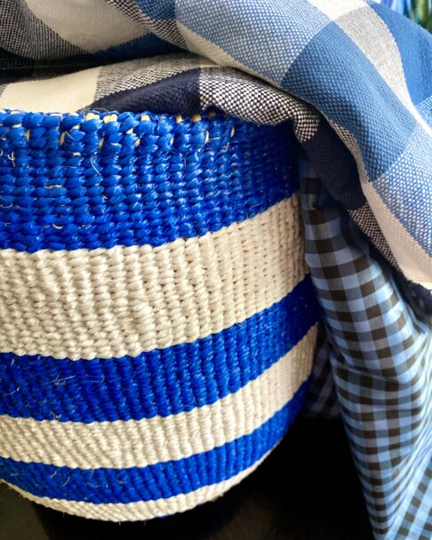 A vibrant, blue and white striped, woven storage basket.