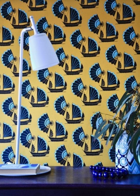 A bold yellow and turquoise wallpaper depicting Chinese junk ships and fans.