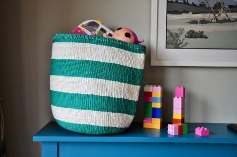 Striped toy storage baskets in jade and white, woven and handmade in Kenya. Filled with colourful kids toys.