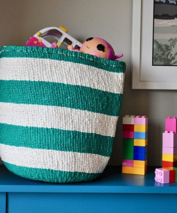 Striped toy storage baskets in jade and white, woven and handmade in Kenya. Filled with colourful kids toys.